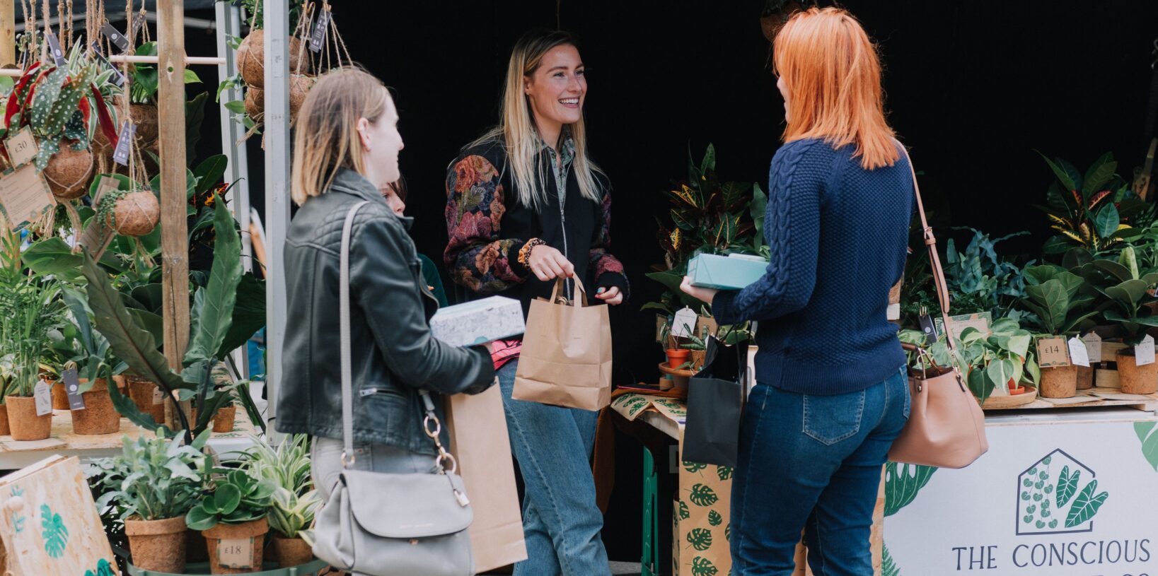 3 people stood around a stall purchasing products