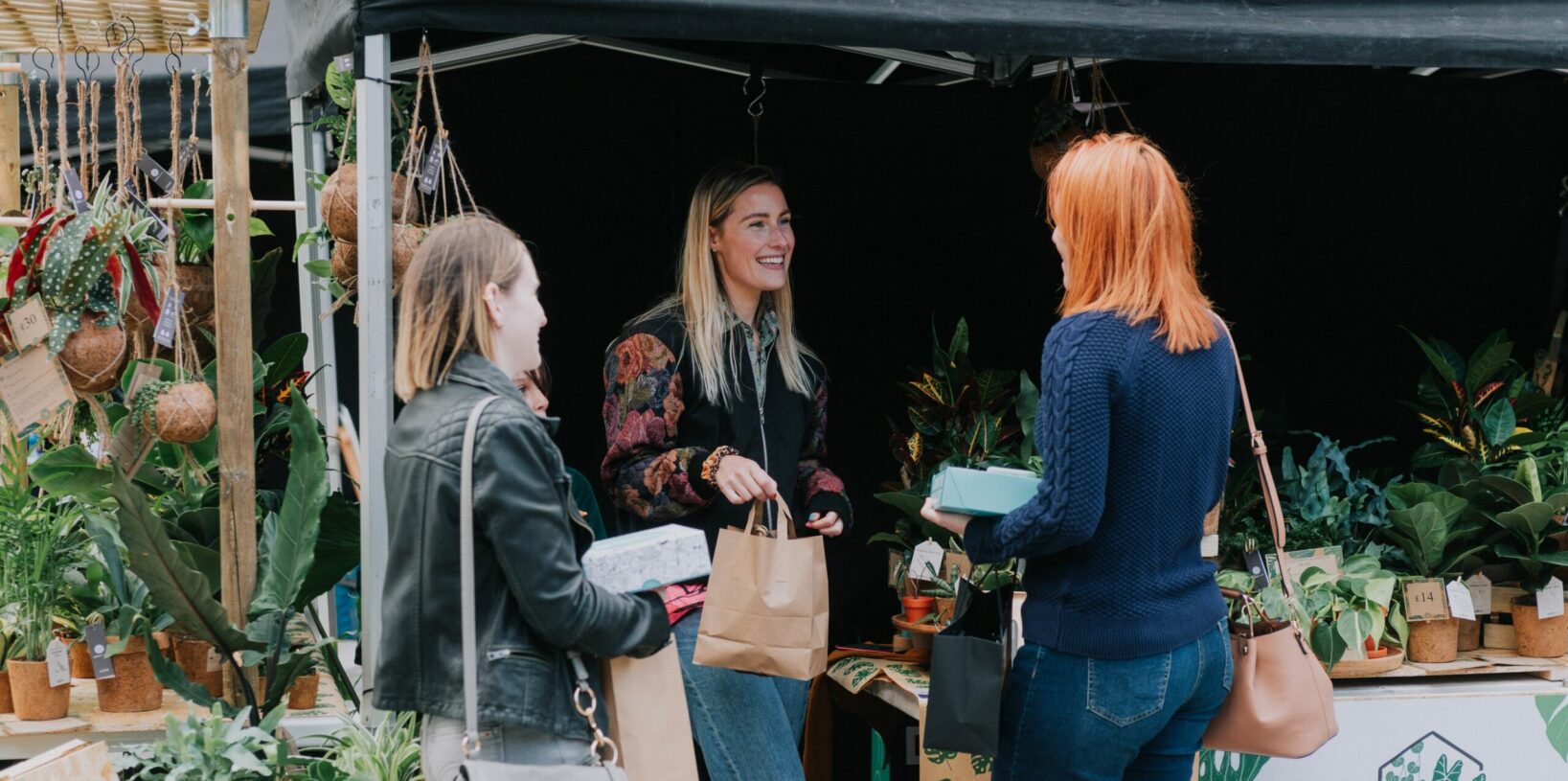 3 people stood around a stall purchasing products