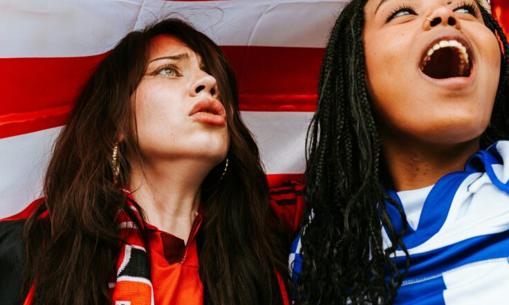 two people looking away from the camera reacting to the football